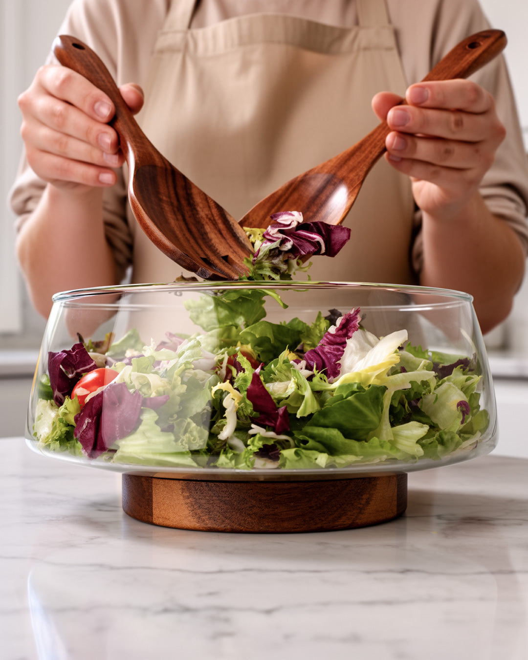 Ensaladera de vidrio con cubiertos de ensalada y soporte