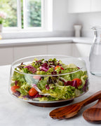 Ensaladera de vidrio con cubiertos de ensalada y soporte